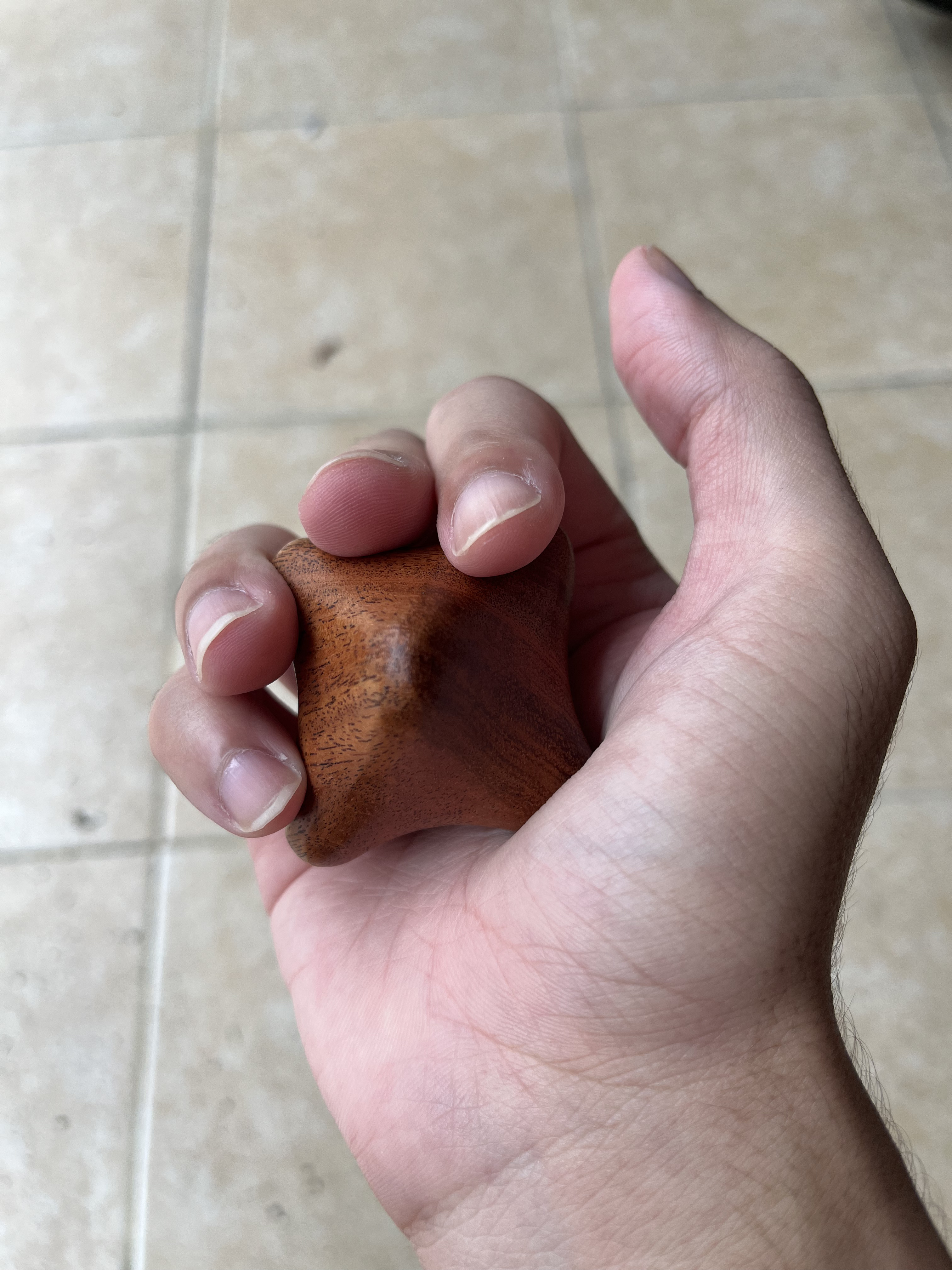 Holding hexagon wooden palm massager in hand